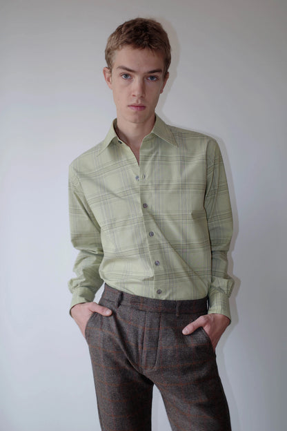 CAMISAS MANOLO（カミサス マノロ）Normal Shirt Pale Green Blue Checksのスタイリング画像。淡いグリーンのチェックシャツをチェック柄のトラウザーにタックインした着用スタイル。自然な生地のドレープと襟元のディテールが特徴。