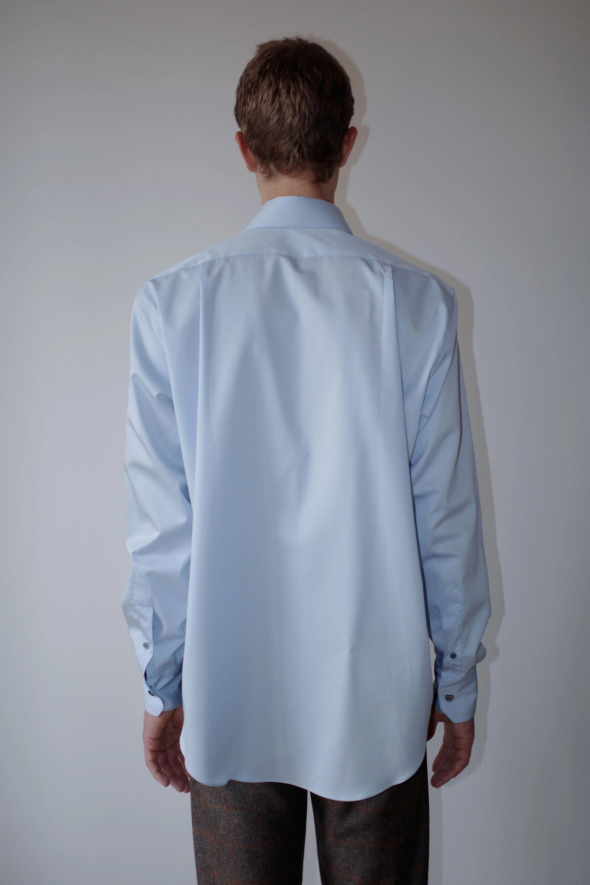 CAMISAS MANOLO（カミサス マノロ）Normal Shirt Light Blue 背面着用画像。ライトブルーの長袖シャツのバックシルエット。背面のヨーク切り替えと緩やかなラウンドヘムが特徴。