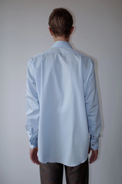 CAMISAS MANOLO（カミサス マノロ）Normal Shirt Light Blue 背面着用画像。ライトブルーの長袖シャツのバックシルエット。背面のヨーク切り替えと緩やかなラウンドヘムが特徴。