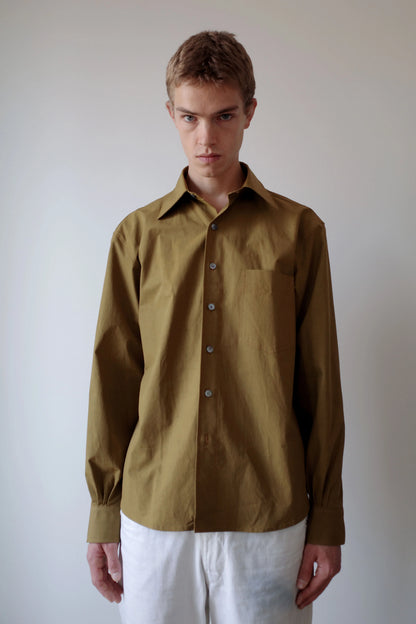 CAMISAS MANOLO（カミサス マノロ）Sobrecamisa Shirt Oliveの正面着用画像。奥行きのあるオリーブカラーの長袖シャツ。ゆとりのあるシルエットと胸元のシングルポケット、緩やかなラウンドヘムが特徴。