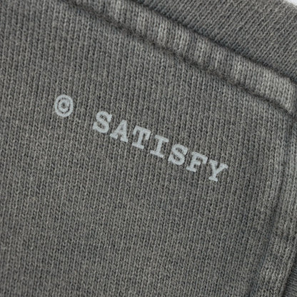 SATISFY MothTech™ Hoodie Faded Blackのロゴディテール。ウォッシュ加工されたコットン生地に配置された©SATISFYロゴ。