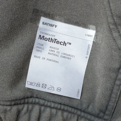 SATISFY MothTech™ Hoodie Faded Blackのケアラベル。衣服の外側に配置された取り外し可能なブランドラベル。